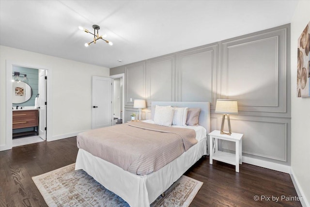 bedroom with ensuite bathroom, dark wood-type flooring, and a notable chandelier