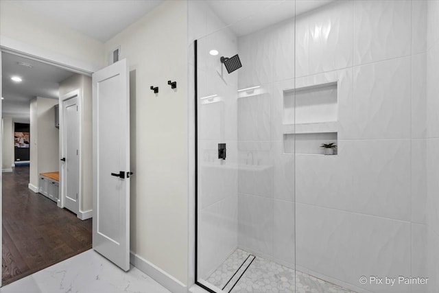 full bathroom with a walk in shower, marble finish floor, and baseboards