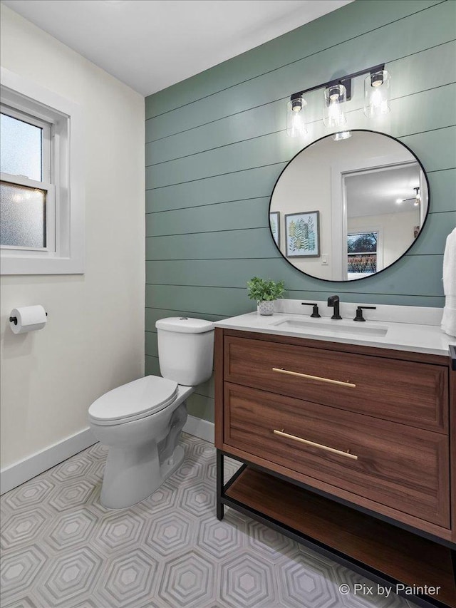 bathroom with wooden walls, baseboards, toilet, tile patterned flooring, and vanity