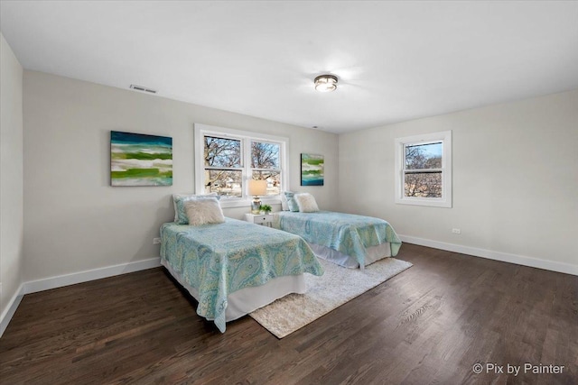 bedroom with baseboards, visible vents, and wood finished floors