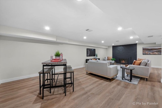 living room featuring a brick fireplace and light hardwood / wood-style flooring