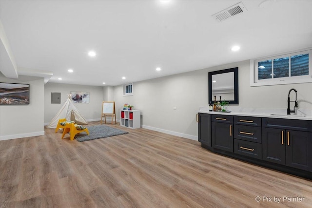 playroom with wet bar, electric panel, and light hardwood / wood-style flooring