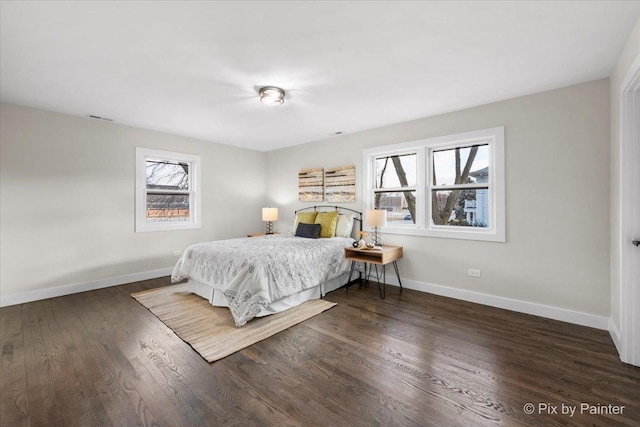 bedroom with multiple windows, visible vents, baseboards, and wood finished floors