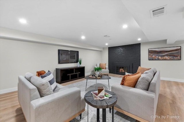 living room featuring a brick fireplace and light wood-type flooring