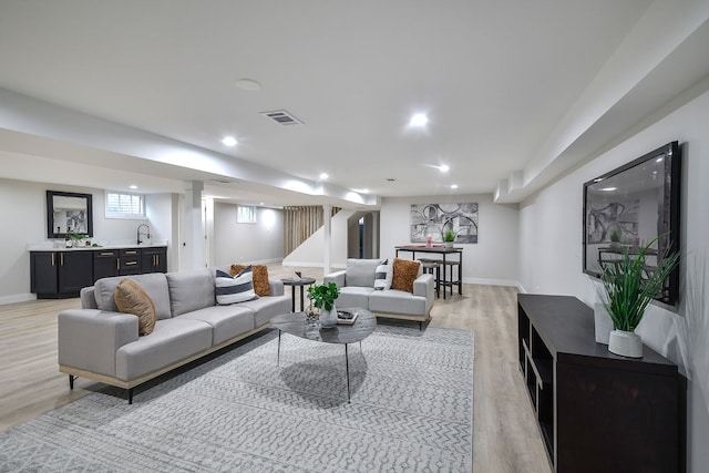 living room with light wood-type flooring, baseboards, visible vents, and indoor wet bar