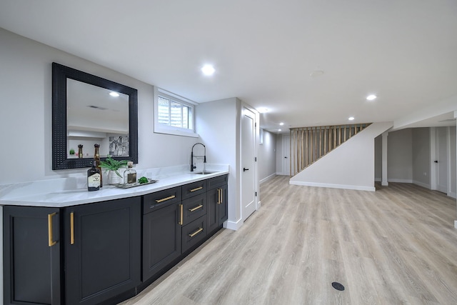 bar with light wood-type flooring, a sink, baseboards, and recessed lighting