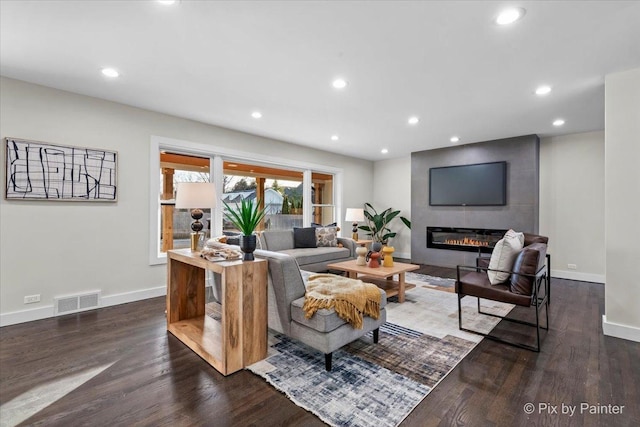 living room featuring dark wood-type flooring and a large fireplace