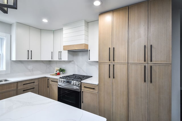 kitchen with light stone counters, gas stove, custom range hood, and backsplash