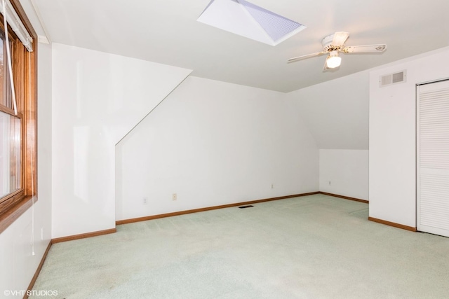 bonus room featuring carpet floors, vaulted ceiling with skylight, visible vents, and baseboards