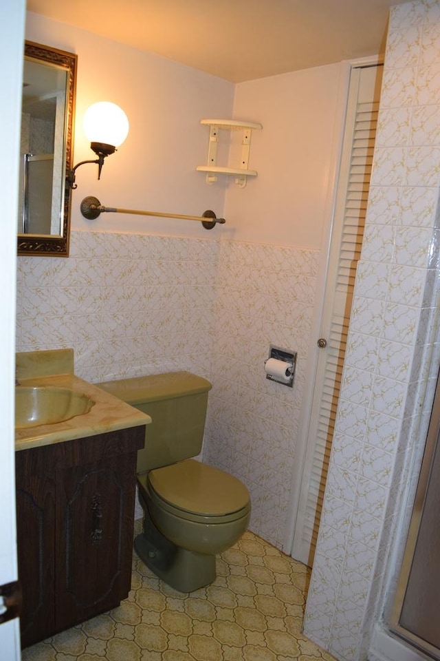 bathroom featuring vanity, tile walls, and toilet