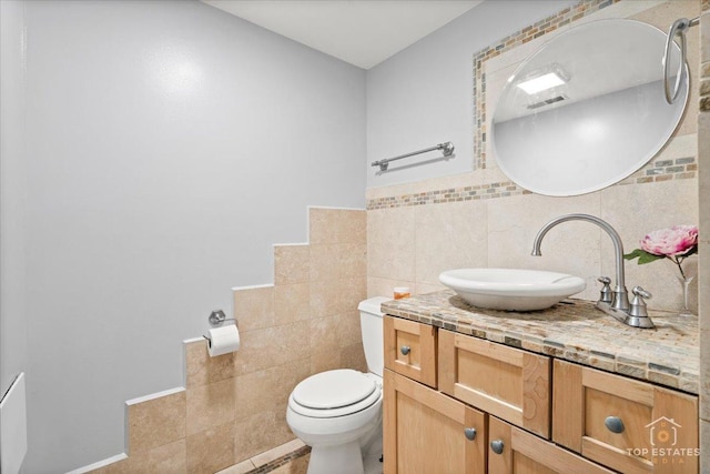 bathroom featuring toilet, tasteful backsplash, tile walls, tile patterned flooring, and vanity