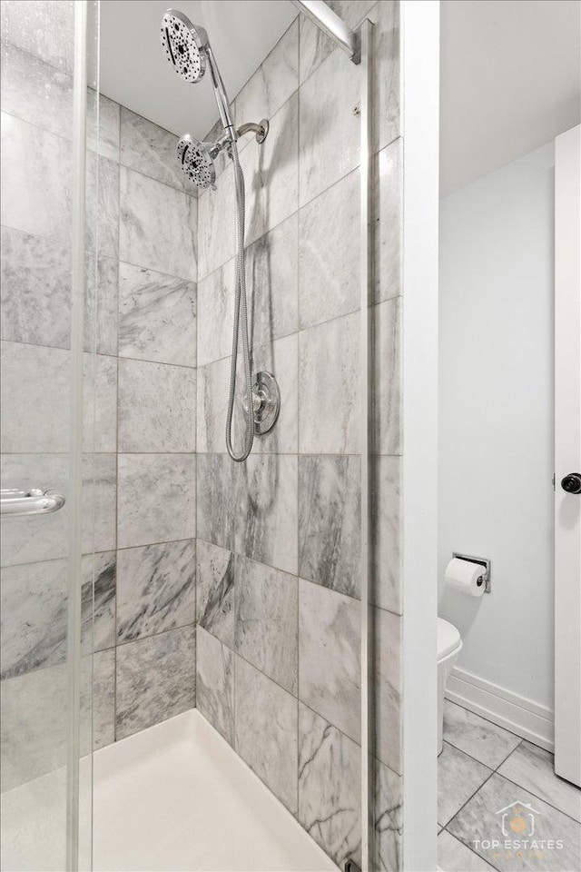 bathroom featuring a shower with door and toilet