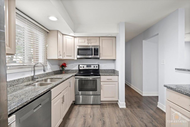 kitchen featuring sink, light stone counters, dark hardwood / wood-style floors, and appliances with stainless steel finishes