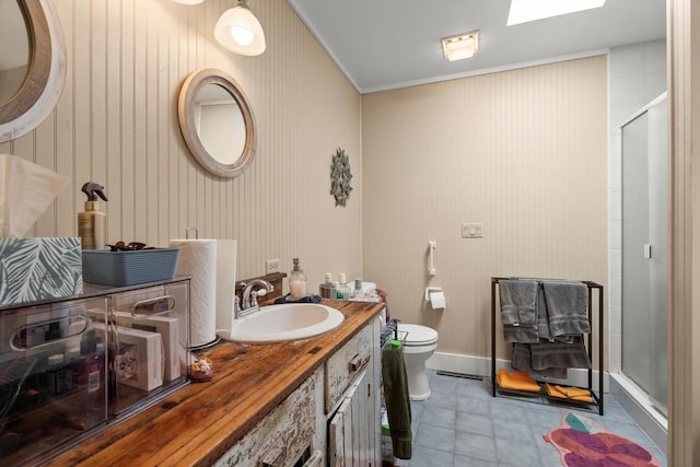 bathroom with toilet, a skylight, ornamental molding, vanity, and a shower with door