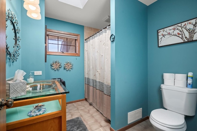 bathroom with toilet, vanity, and a skylight