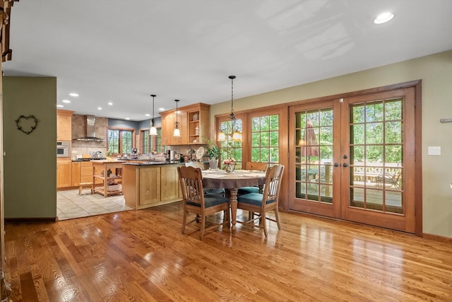 dining room with an inviting chandelier, french doors, and light wood-type flooring