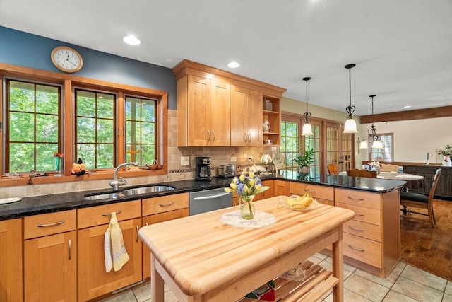 kitchen featuring stainless steel dishwasher, sink, decorative light fixtures, light tile patterned flooring, and a center island