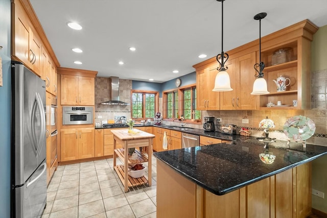 kitchen with kitchen peninsula, hanging light fixtures, appliances with stainless steel finishes, wall chimney exhaust hood, and backsplash