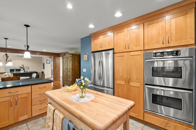 kitchen featuring hanging light fixtures, light tile patterned floors, a kitchen island, stainless steel appliances, and butcher block countertops