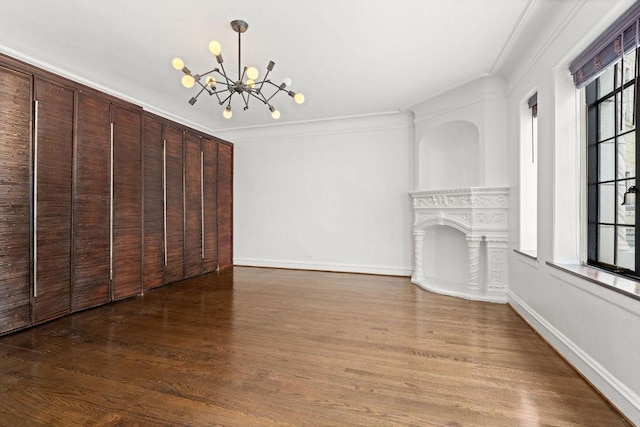 unfurnished living room featuring a notable chandelier, hardwood / wood-style flooring, and ornamental molding