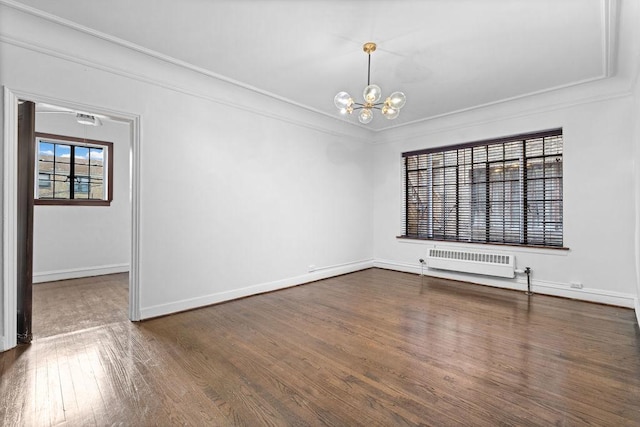 spare room with an inviting chandelier, crown molding, radiator, and dark wood-type flooring