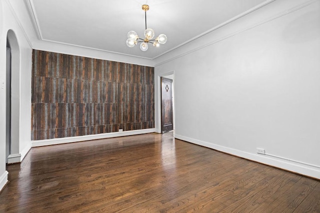 unfurnished room with crown molding, dark hardwood / wood-style floors, and an inviting chandelier