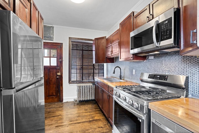 kitchen with sink, crown molding, appliances with stainless steel finishes, radiator heating unit, and decorative backsplash