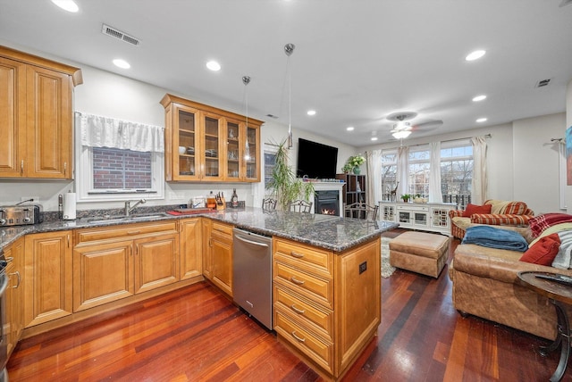 kitchen featuring dark hardwood / wood-style floors, sink, dark stone counters, stainless steel dishwasher, and kitchen peninsula