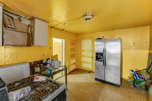 kitchen with stainless steel fridge with ice dispenser, light parquet flooring, and range with gas stovetop