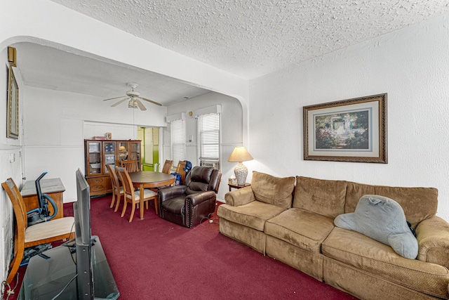 carpeted living room featuring ceiling fan and a textured ceiling