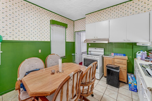 kitchen with white electric range, white cabinetry, light tile patterned floors, and a textured ceiling