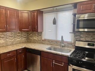 kitchen with light stone countertops, appliances with stainless steel finishes, sink, and backsplash