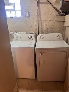 laundry area with washing machine and clothes dryer and light tile patterned floors