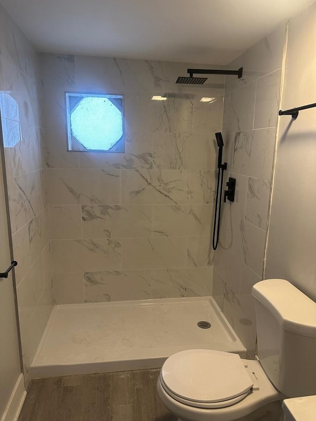 bathroom with a tile shower, toilet, and hardwood / wood-style floors