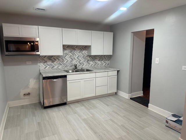 kitchen with tasteful backsplash, stainless steel appliances, sink, and white cabinets