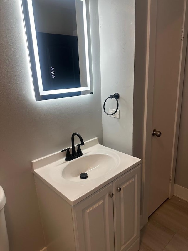 bathroom featuring vanity, hardwood / wood-style floors, and toilet