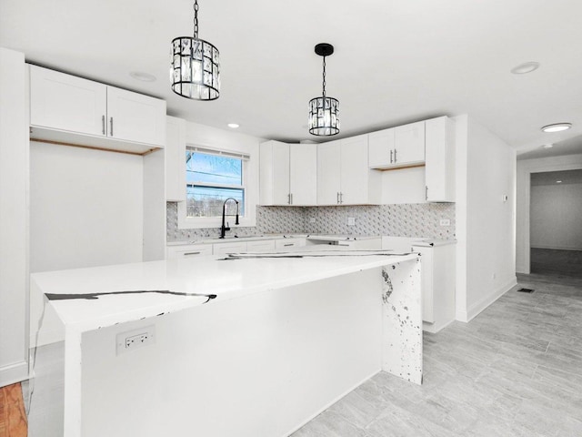 kitchen featuring hanging light fixtures, a center island, sink, and white cabinets