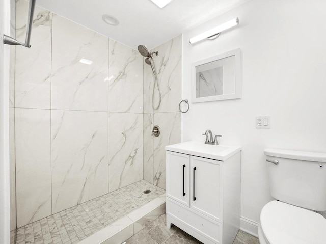 bathroom with vanity, toilet, and a tile shower