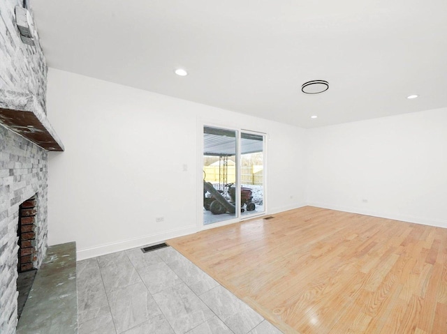 unfurnished living room featuring a brick fireplace and light wood-type flooring