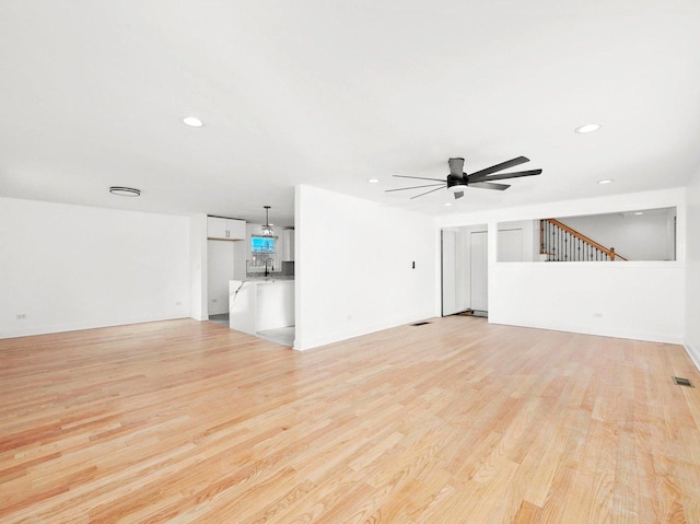 unfurnished living room with sink, light hardwood / wood-style flooring, and ceiling fan