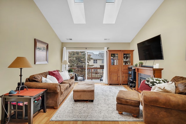 living room featuring vaulted ceiling with skylight and light hardwood / wood-style floors