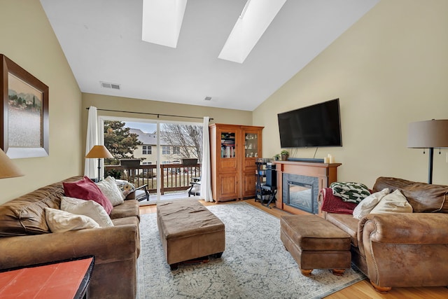 living room featuring a fireplace, vaulted ceiling with skylight, and hardwood / wood-style floors