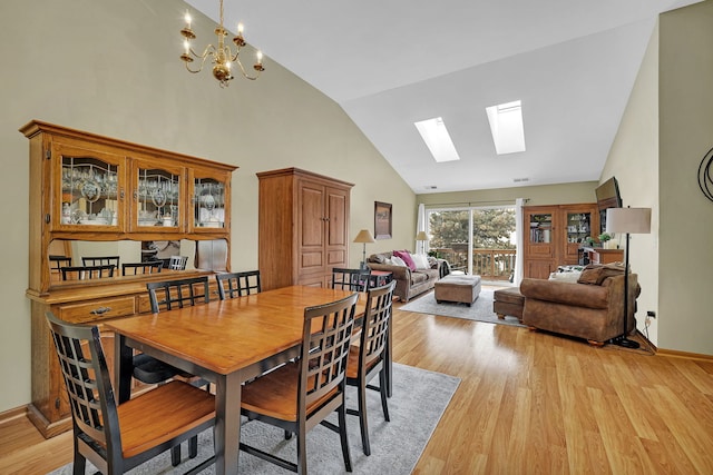 dining area with vaulted ceiling with skylight, a notable chandelier, and light wood-type flooring