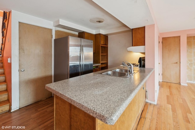 kitchen featuring stainless steel fridge, kitchen peninsula, sink, and light hardwood / wood-style flooring