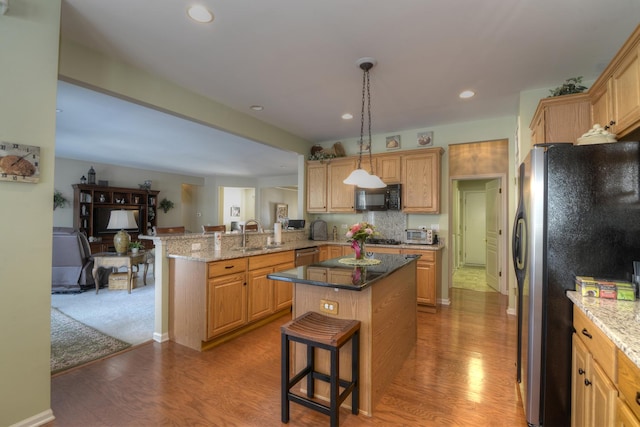 kitchen featuring pendant lighting, sink, a kitchen breakfast bar, kitchen peninsula, and stainless steel appliances