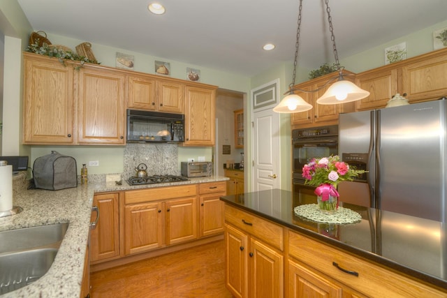 kitchen featuring pendant lighting, decorative backsplash, black appliances, and dark stone countertops