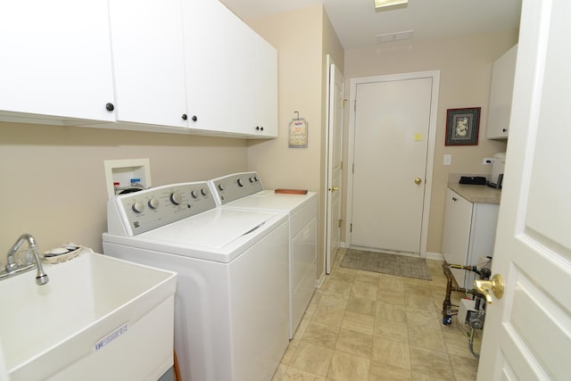 clothes washing area with sink, washer and clothes dryer, and cabinets