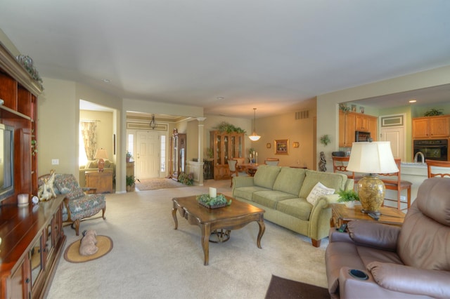 living room featuring ornate columns and light carpet