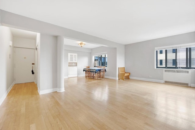 unfurnished living room featuring radiator heating unit and light wood-type flooring