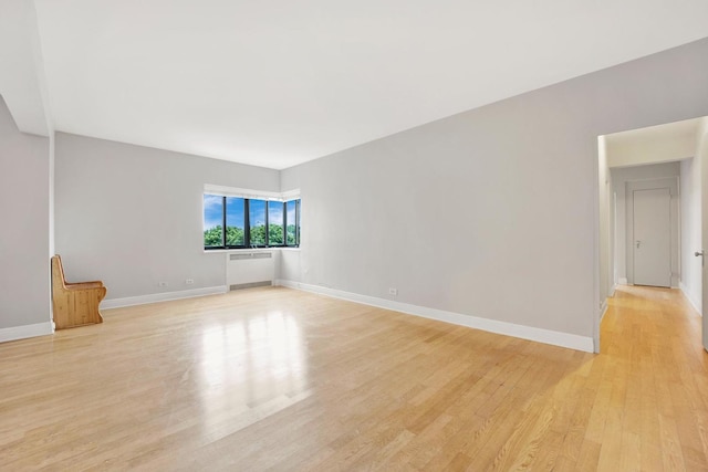 unfurnished living room with radiator and light wood-type flooring